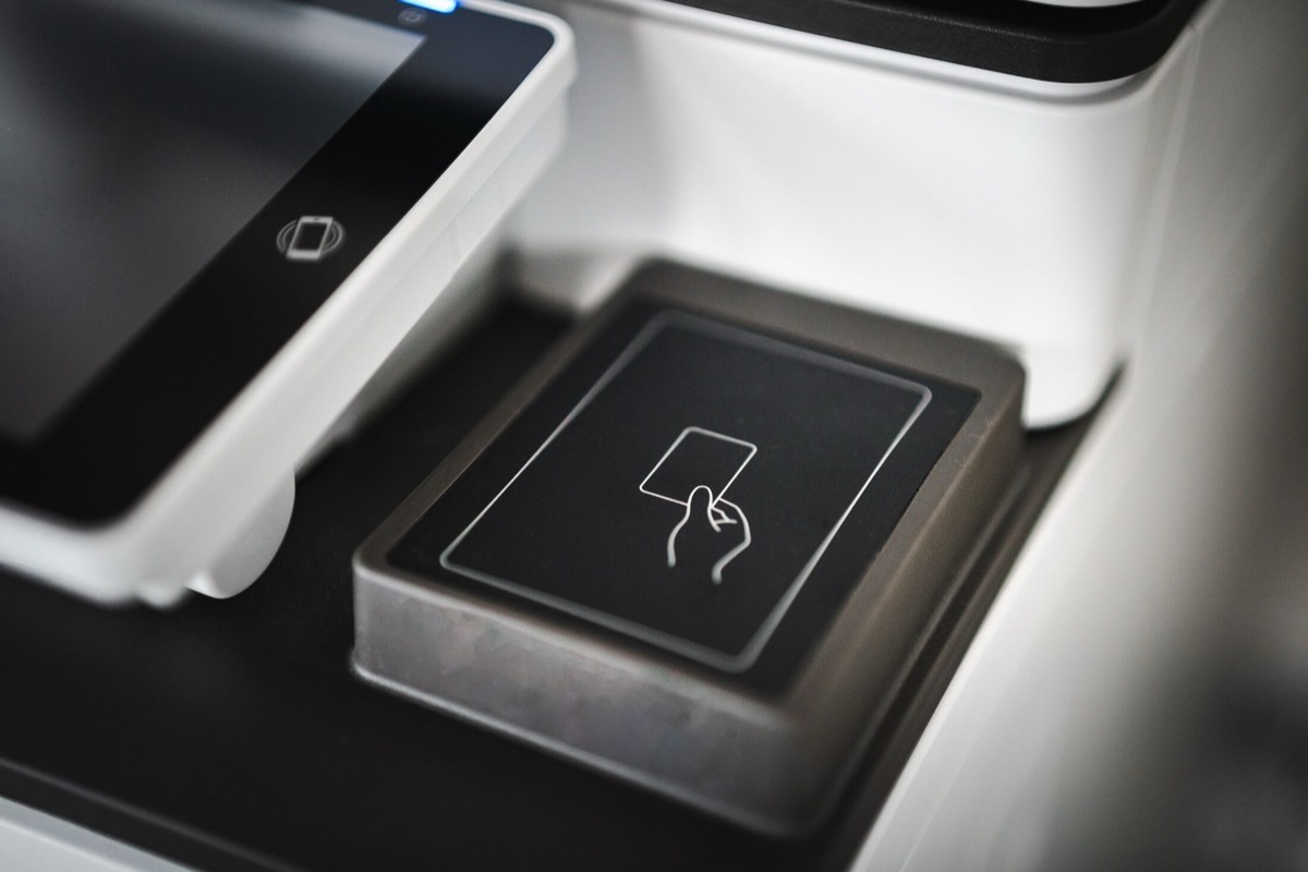 A sleek contactless card payment terminal with the tap-to-pay icon