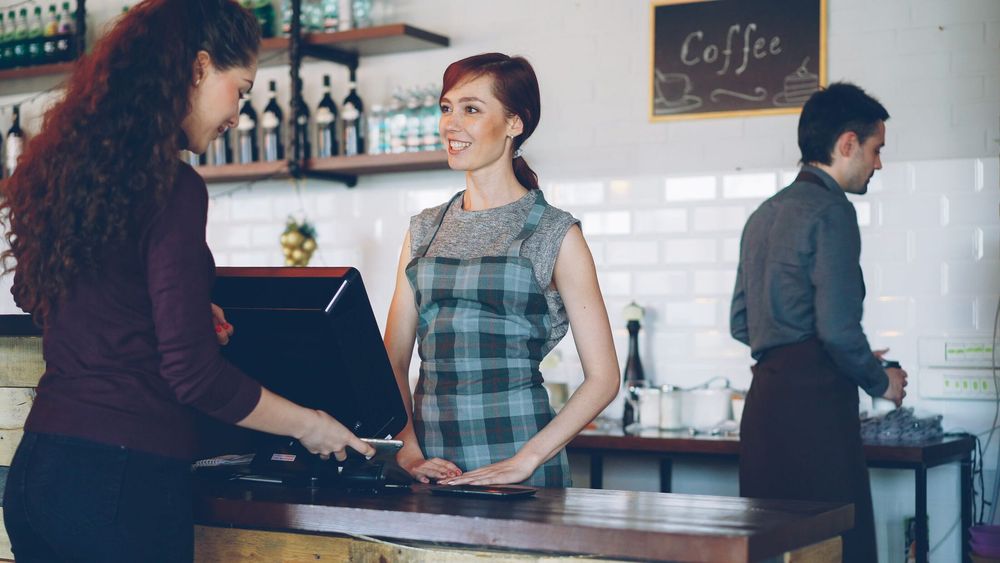 A customer being served by staff at the counter of a coffee shop